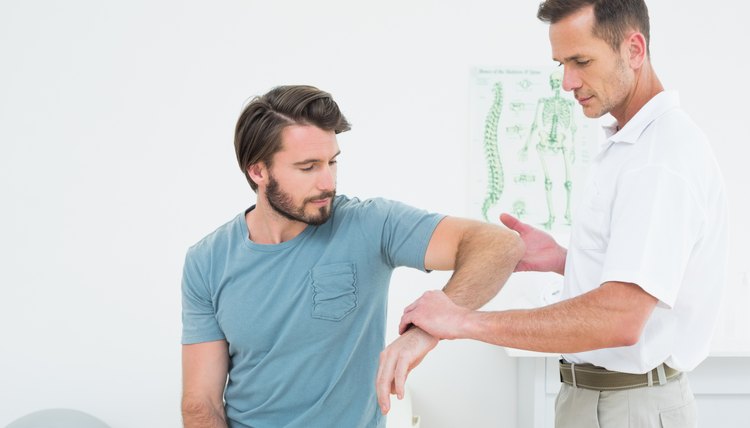Male physiotherapist examining a young man's arm