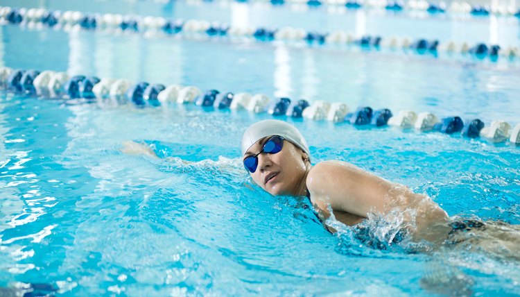 Young girl in goggles swimming front crawl stroke style