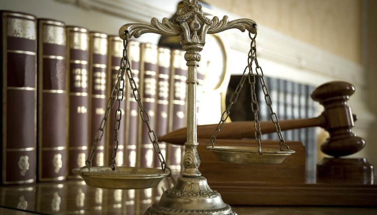Justice scales, a gavel, and law books on a marble counter.