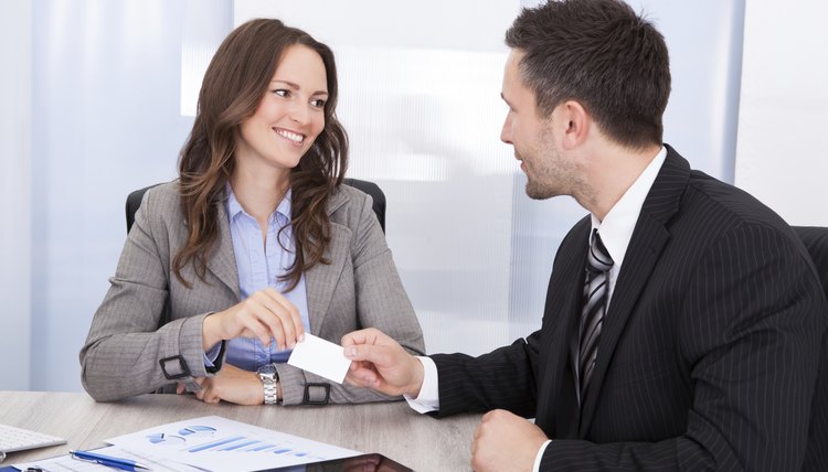Businessman And Businesswoman Exchanging Visiting Card At Office Desk
