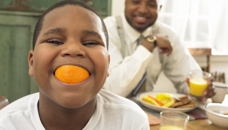 Boy with an orange in his mouth.
