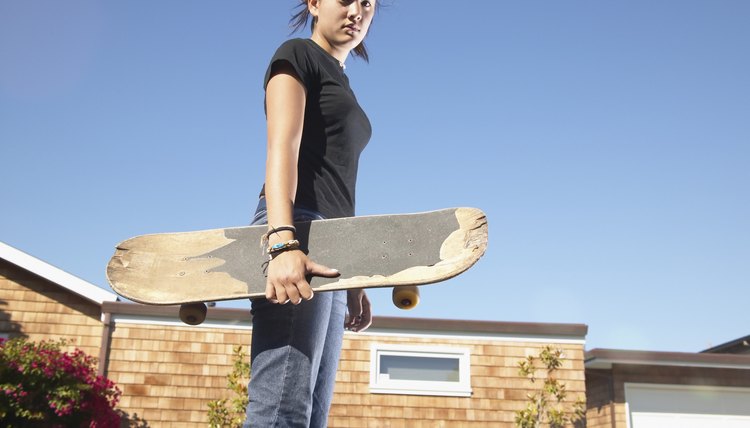Low angle view of a teenage girl holding a skateboard