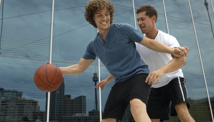 Two young men playing basketball outside office
