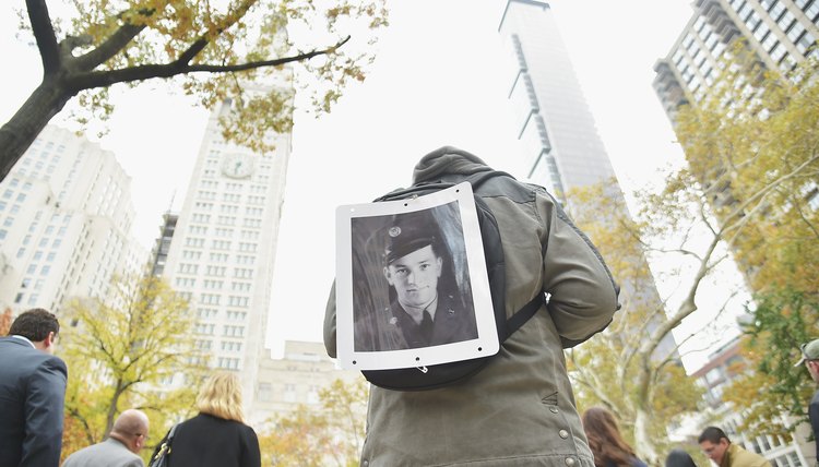 A parade attendee on Veteran's Day exhibiting a portrait of his grandfather who served in the military.