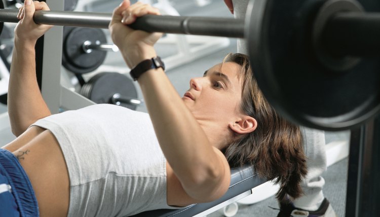 young hispanic woman working out at the gym lifting weights