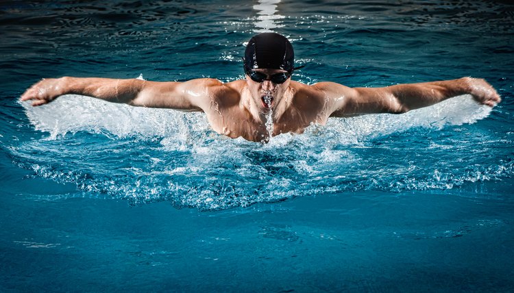 Muscular young man swims the butterfly in the pool