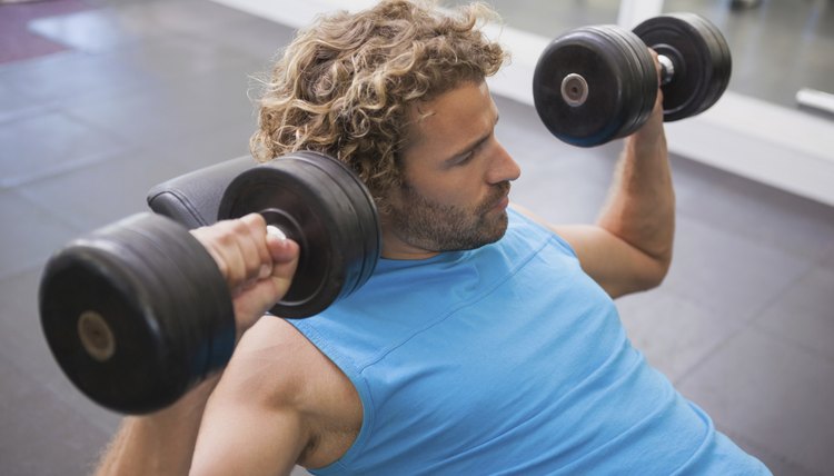 Side view of man exercising with dumbbells in gym