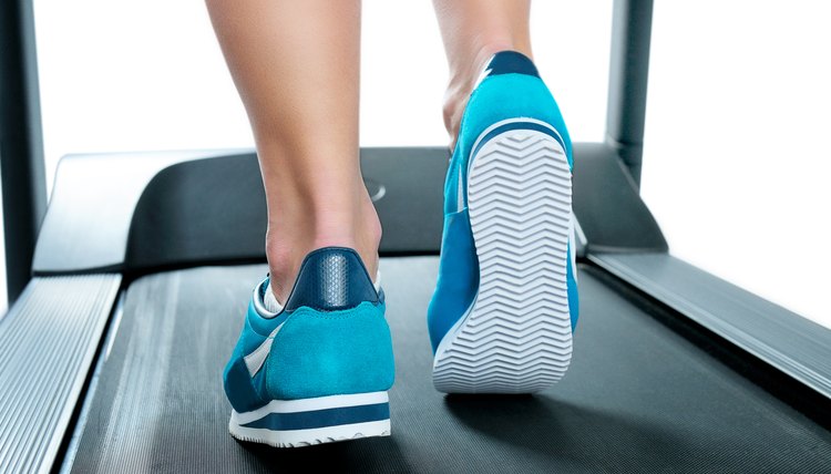 Female legs in turquoise sneakers on a treadmill.