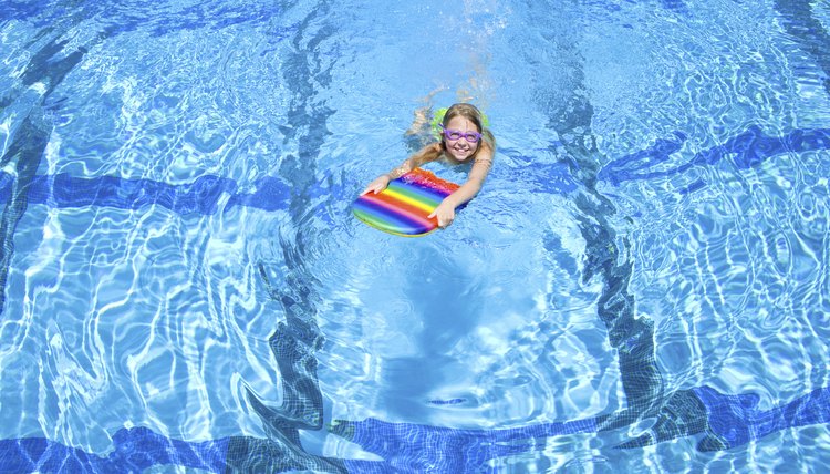 Young girl using paddle board in swimming pool