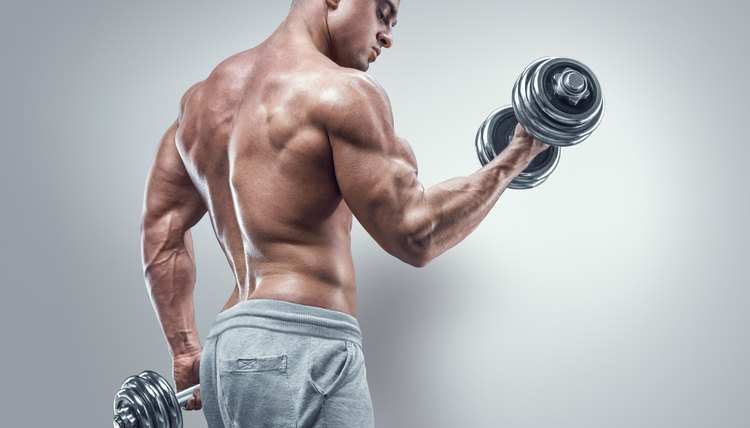 Power athletic man in training pumping up muscles with dumbbells