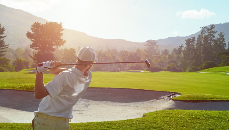 golf man takes a swing over bunker