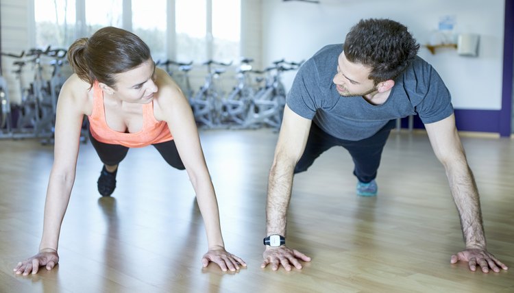 Couple training in fitness studio exercising push ups
