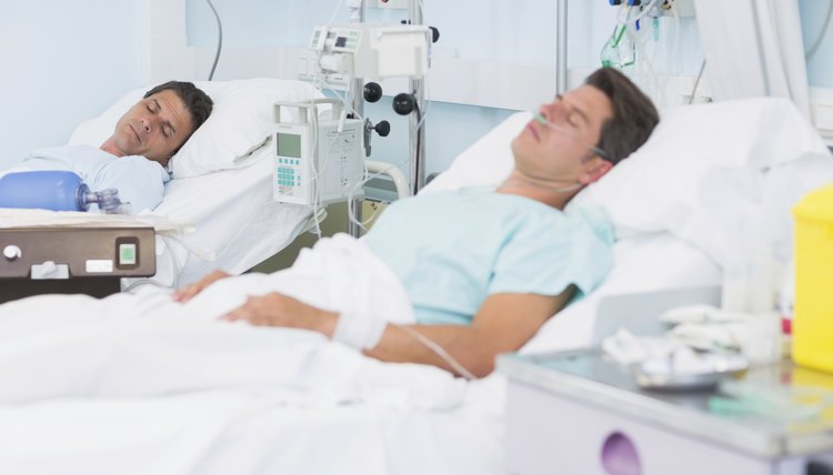 Two male patients asleep in hospital beds.