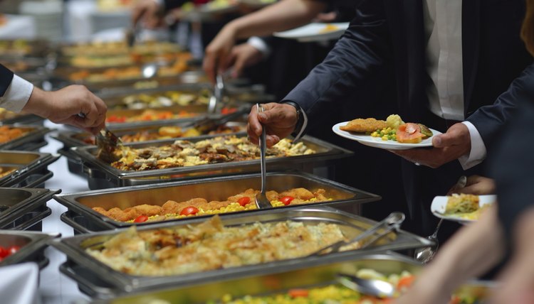 People gather around the buffet to help themselves to food