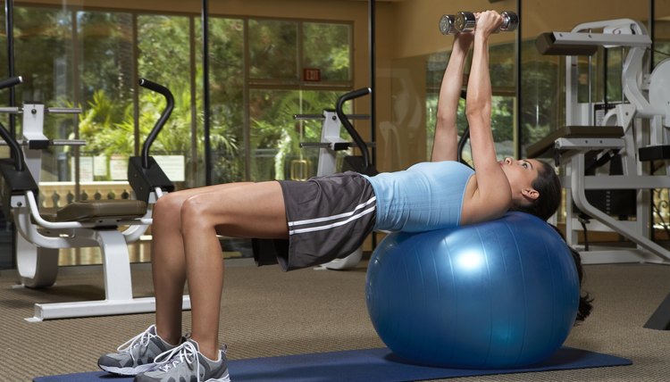 Woman exercising with dumbbells on fitness ball