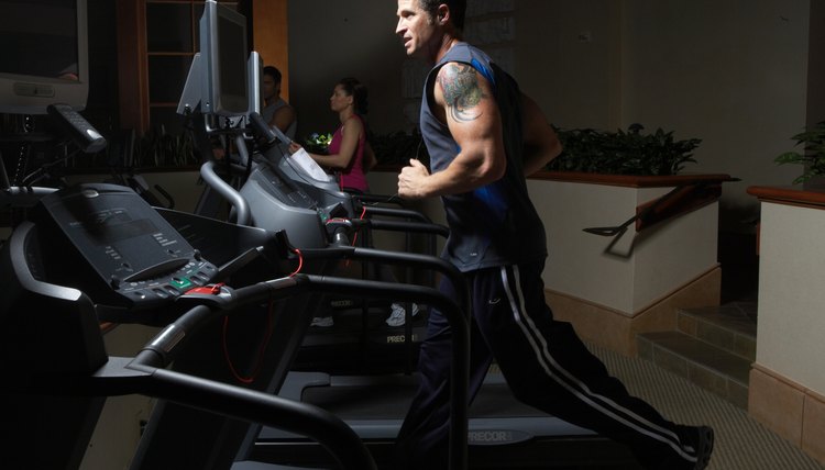 Men and woman exercising on treadmill in gym, side view