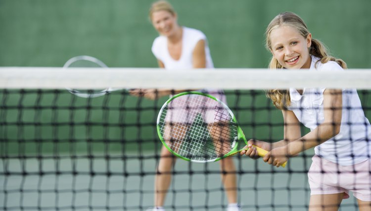 Girl playing tennis with parent