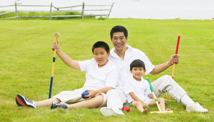 Man with two young boys sitting on a lawn