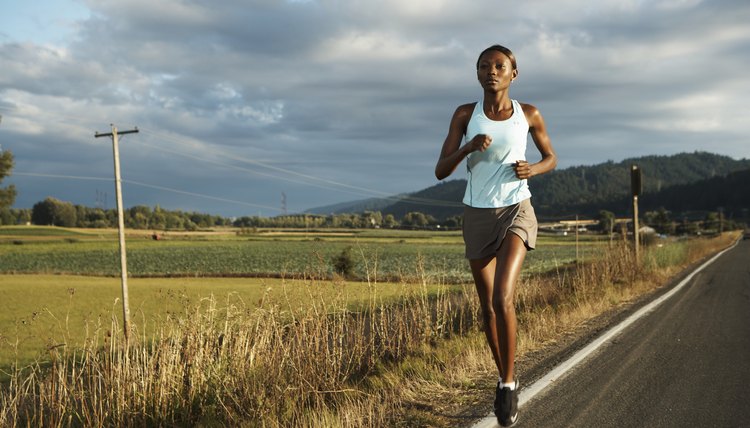 Young woman jogging by road in rural landscape