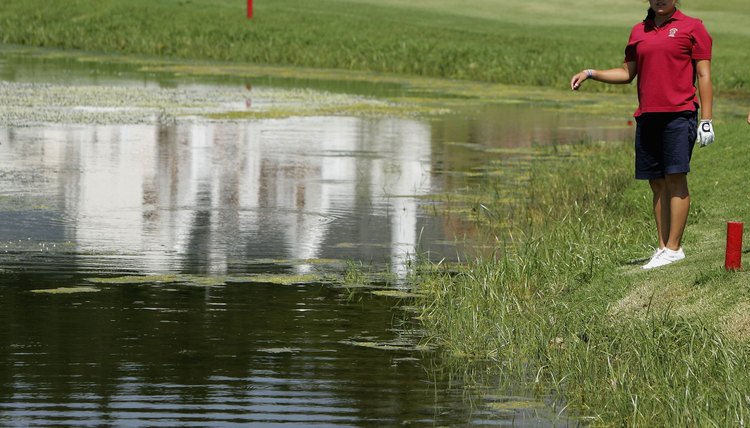 Jennie Lee searches for her ball in a lateral water hazard defined by red stakes at South Africa's De Zatze Golf Club.