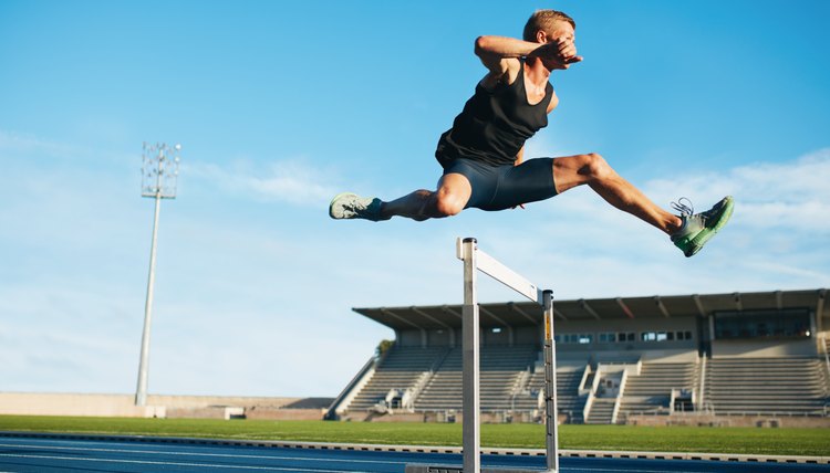 Professional sprinter jumping over a hurdle