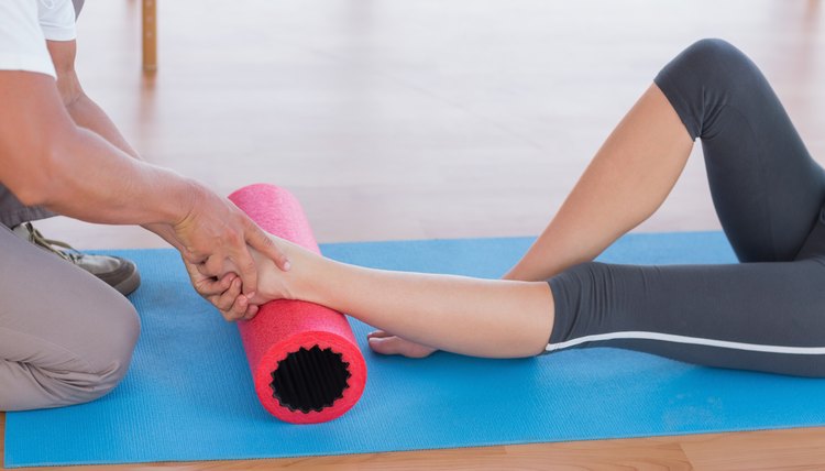 Trainer working with woman on exercise mat