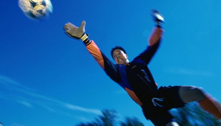 Low angle view of a teenage goalie reaching for the ball