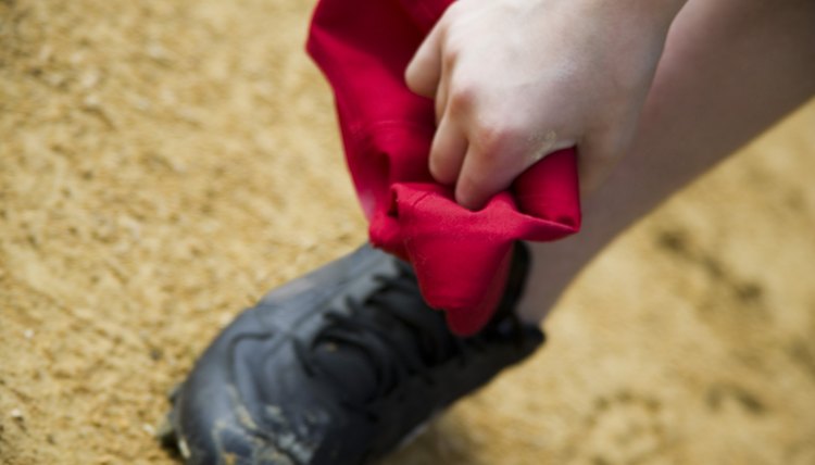 Close-up of person holding cap and wearing baseball cleats