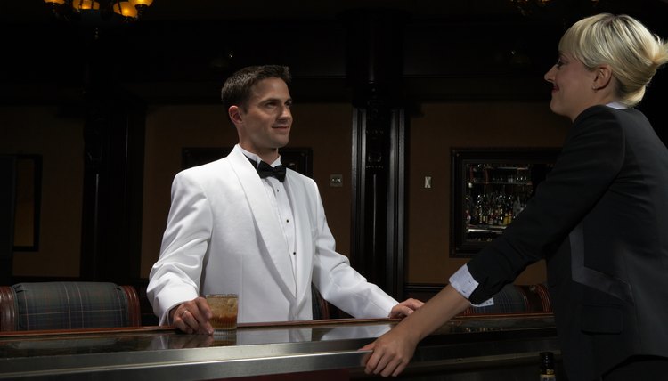 A bartender wears a white tuxedo jacket.