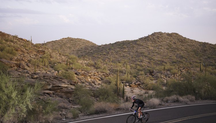 Young man riding bicycle along desert road