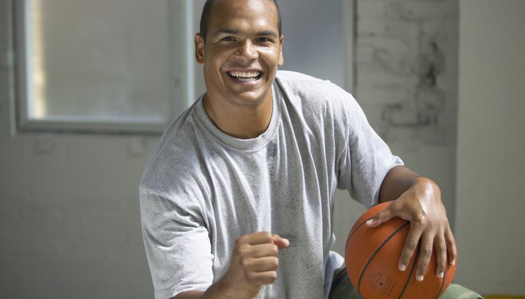 Portrait of mid adult man standing on one leg holding a basketball