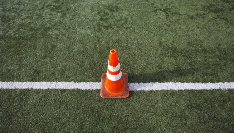 Orange cone on football field.