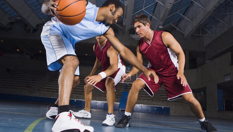 Man dribbling basketball against defenders