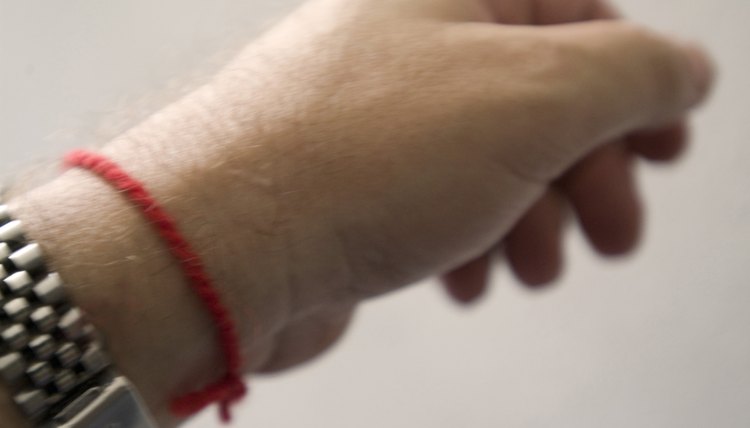 A close-up of a kabbalah red string tied around a person's wrist.