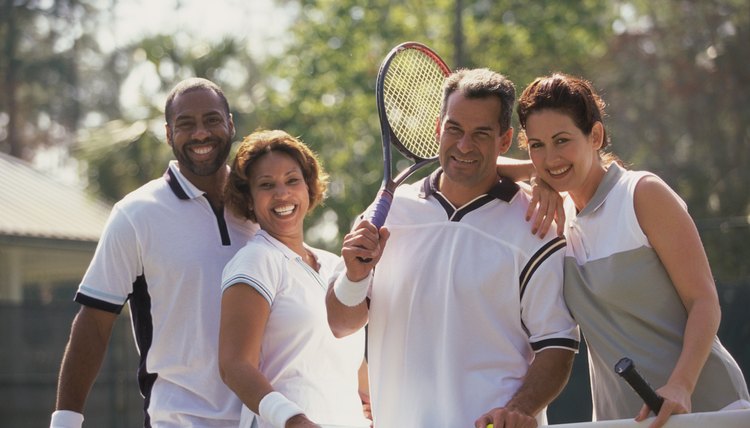 Portrait of two mid adult couples smiling on a tennis court