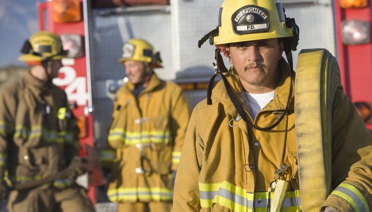 Portrait of firefighter carrying hose