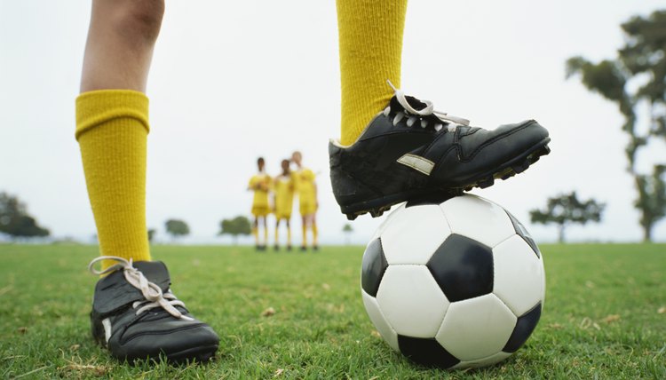 low section view of a person with his one leg on a soccer ball