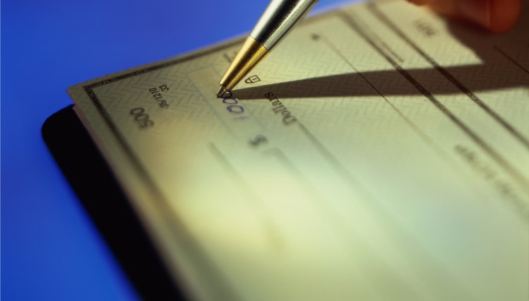 close-up of a hand writing the amount on a bank cheque