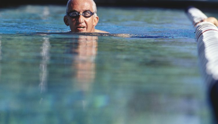 Senior man swimming in outdoor pool, surface view