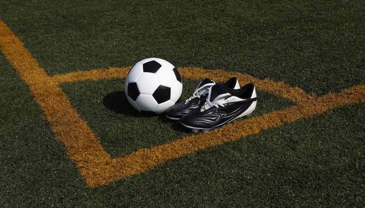 Soccer ball and cleats in corner of soccer pitch, elevated view