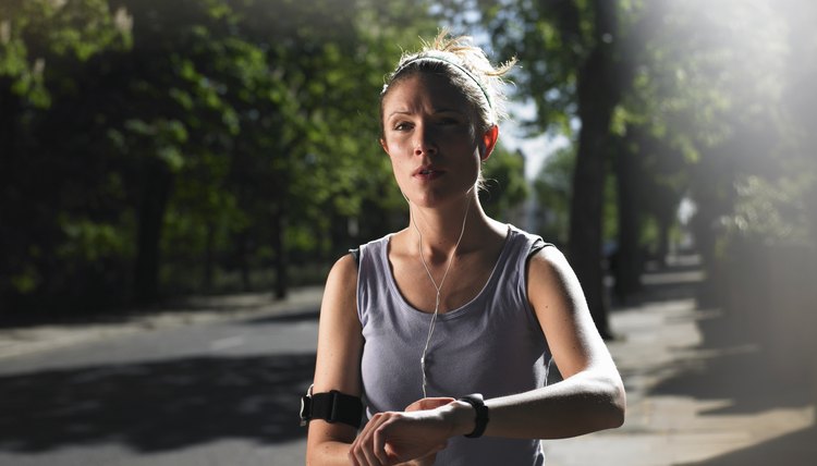 Young woman jogging on street with mp3 player, checking time
