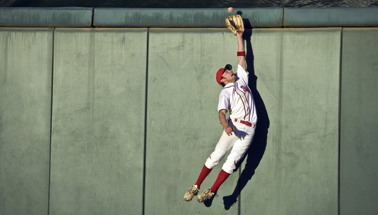 USA, California, San Bernardino, baseball player making leaping catch at wall