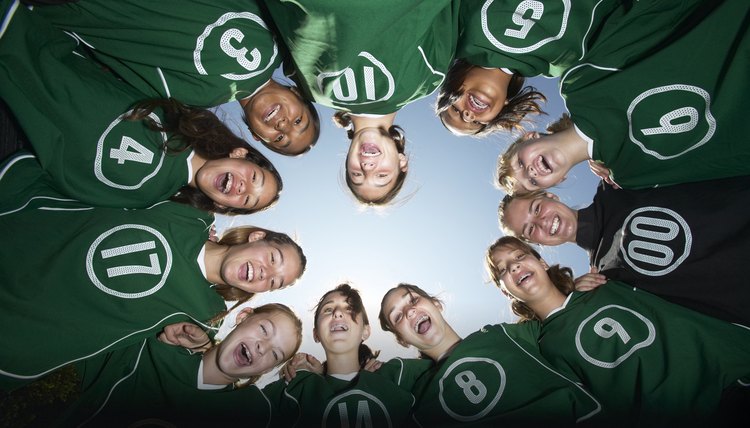 Girls (12-15) football team forming huddle, view from below