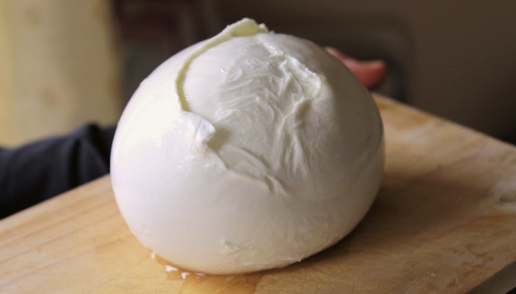 A ball of mozzarella cheese on a wood cutting board.