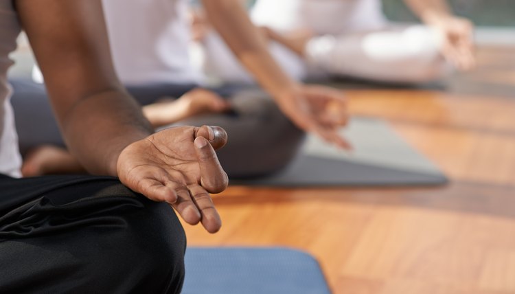 Hand of man sitting on yoga mat and meditating