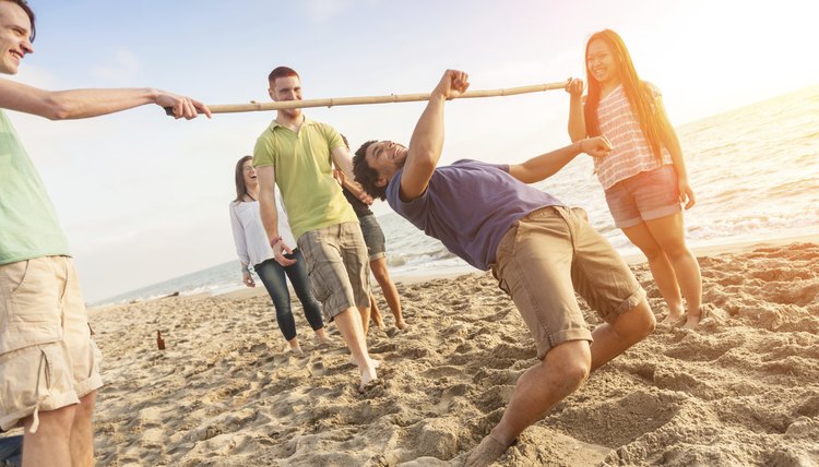 Friends dancing the limbo on the beach.