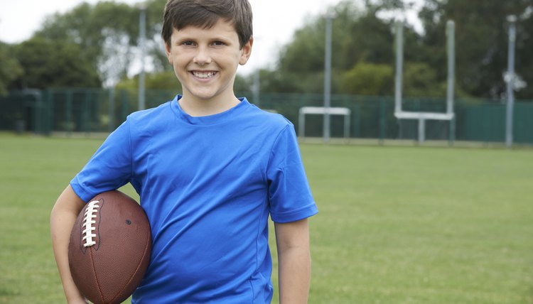 Portrait Of Boy Holding Ball On School Football Pitch