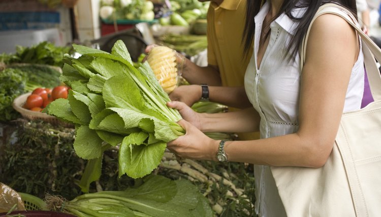 Woman buying fresh vegetables at market, Vietnam