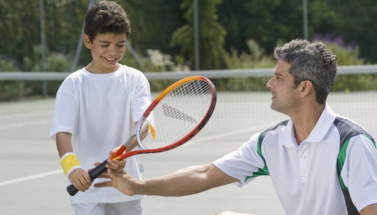 Man teaching boy to play tennis