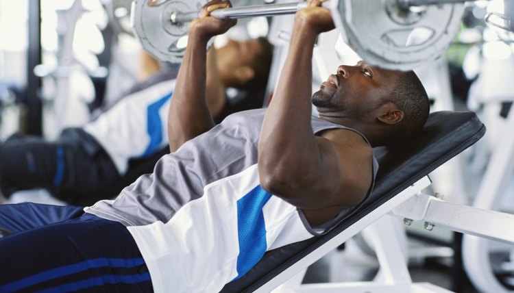 Two mid adult men exercising in a gym with weights